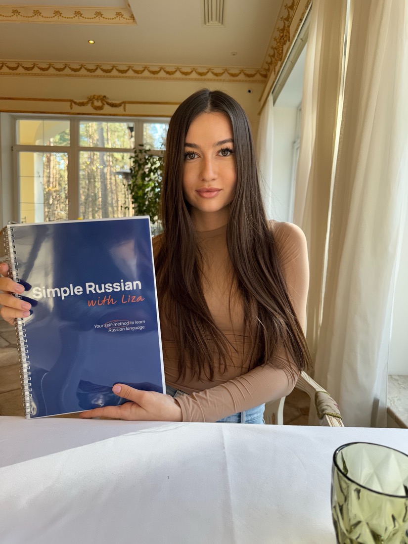 Liza holding the printed Simple Russian with Liza spiral workbook